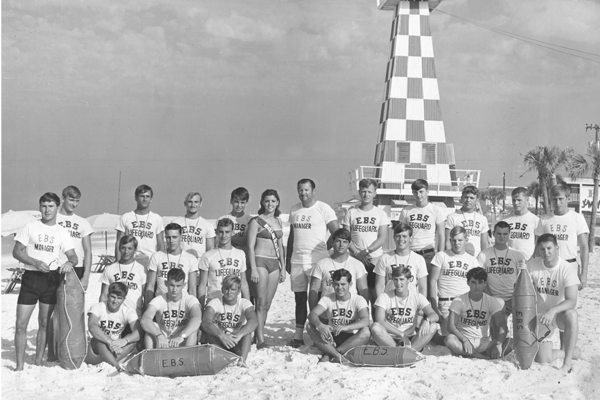 Ed Hickey Jr. is shown standing at center with Miss Long Beach 1967 Marie Savage, and the lifeguards of Ed’s Beach Service on Panama City Beach. (Photo credited to Bob Hargis)